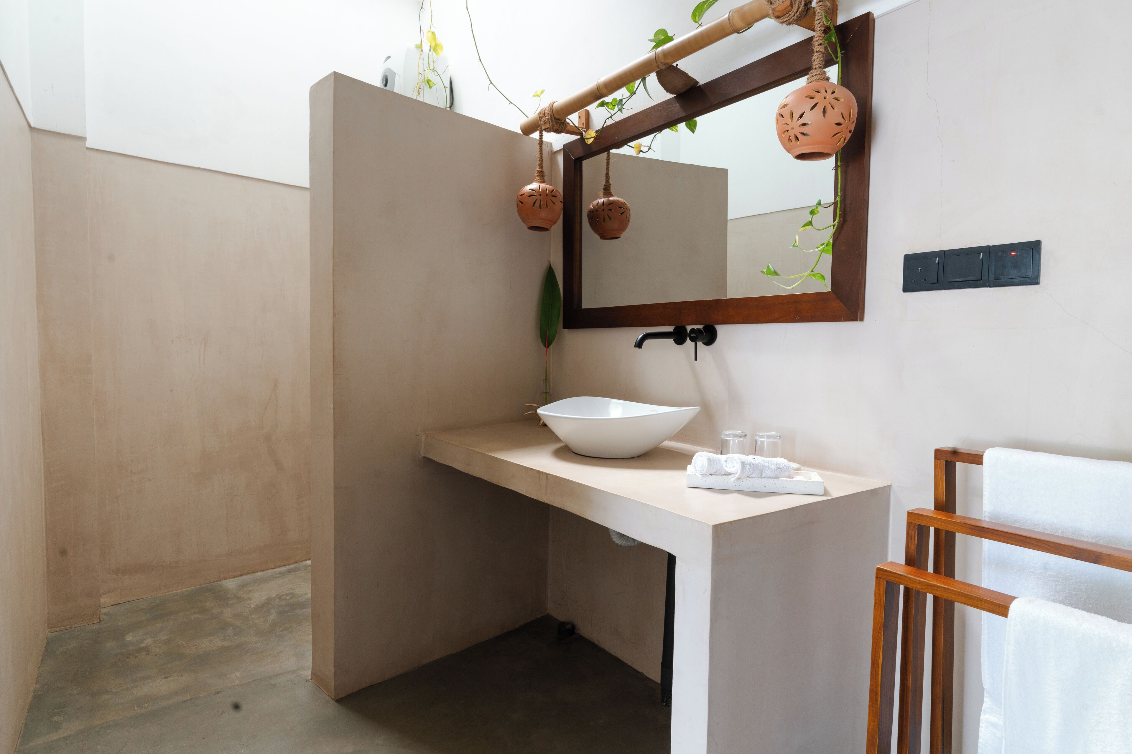 Un baño moderno con un espejo grande, un lavamanos blanco y un perchero de madera.