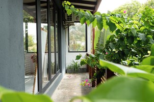 Un espacio al aire libre techado con piso de concreto, plantas en macetas y una planta colgante con hojas verdes.