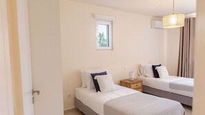 Une chambre avec deux lits, une fenêtre, un appareil de climatisation, une table de chevet avec une lampe et un luminaire suspendu.