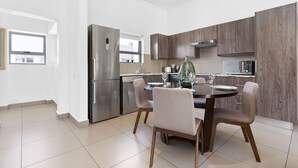 Una cocina moderna con comedor, que incluye un refrigerador de acero inoxidable, gabinetes de madera y una mesa redonda con sillas.