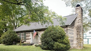 A rustic stone building with a covered porch and an American flag.