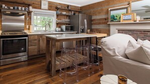 A modern kitchen with wooden accents, stainless steel appliances, and a bar area with stools.