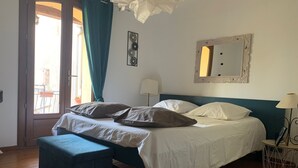 A bedroom with a bed, a bedside table, a lamp, a mirror, and a window with curtains. - Close to Gréoux les bains, 1 bedroom for 2 + a small one for 1 and the swimming pool! (Saint-Julien)