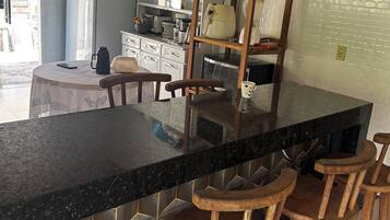 A kitchen with a black countertop, wooden stools, and a white refrigerator.