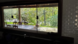 Uma janela com vista para um pátio, incluindo uma mesa, cadeiras e uma planta cacto.