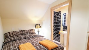 A bedroom with a bed, a bedside lamp, and a bathroom visible through an open door. - Crea The Mission Hall (Antrim)