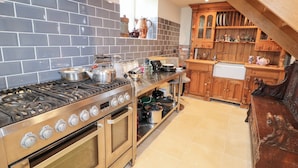 A kitchen with a gas stove, oven, and wooden cabinets. - Crea The Mission Hall (Antrim)