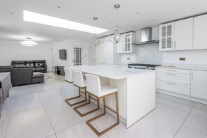 A modern kitchen with a central island, white cabinetry, and a dining area with a sofa and chairs.