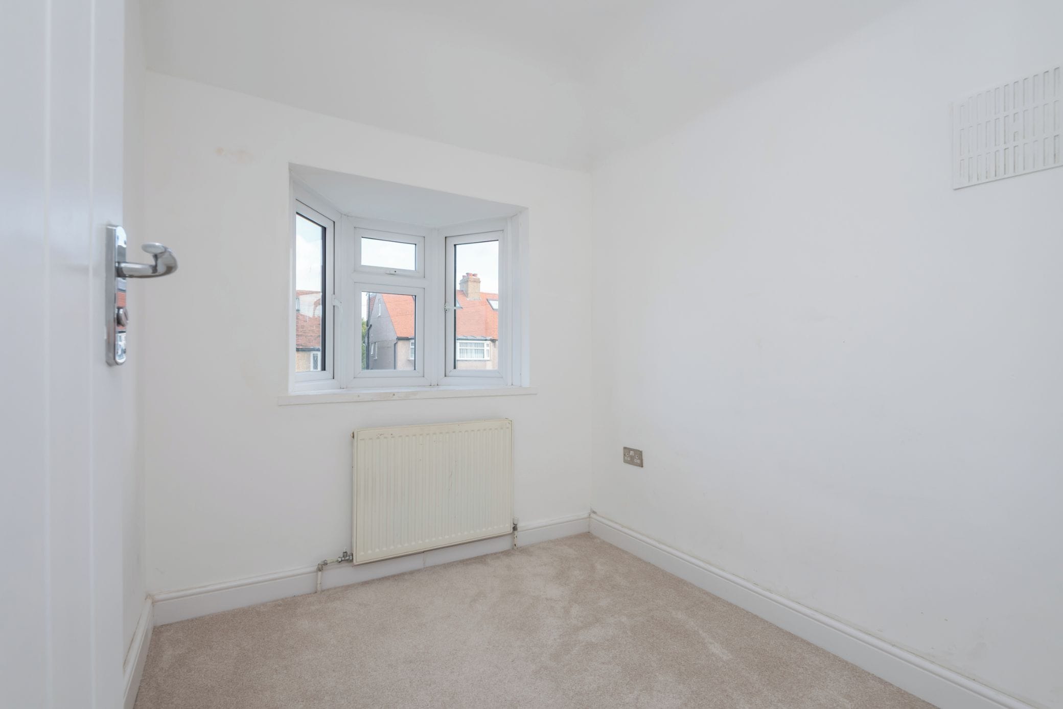 Ein Zimmer mit Heizkörper, Fenster und Tür.