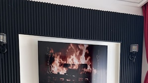Un saló modern amb un gran televisor de pantalla plana fixat a una paret negra amb panells acústics.