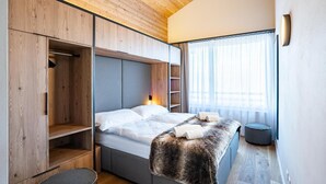 A modern bedroom with a built-in wardrobe, a bed with a fur throw, and a large window with sheer curtains. - Wifi, 150m from ski lifts, terrace, balcony, tv, ski locker, 70-73m², Thyon (Hérémence)