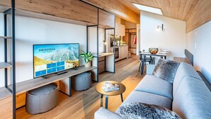 A modern living room with a television displaying a travel website, a sofa, a coffee table, and a dining area with a table and chairs. - Wifi, 150m from ski lifts, terrace, balcony, tv, ski locker, 70-73m², Thyon (Hérémence)