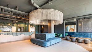 A modern lobby with a central seating area, a reception desk, and a large, circular light fixture. - Wifi, 150m from ski lifts, terrace, balcony, tv, ski locker, 74-84m², Thyon (Hérémence)