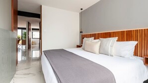 Une chambre d’hôtel moderne avec un grand lit, une tête de lit en bois et un sol en marbre.