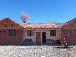 Un edificio de dos pisos con techo de tejas rojas, un porche cubierto y una entrada de grava.