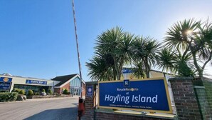 Ein Hotel Eingang mit einem Schild für Royale Resorts auf Hayling Island, einem Empfangsbereich und einer Palm Bar.