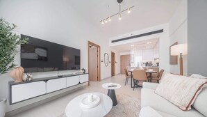 Uma sala de estar moderna com um sofá, mesa de centro e uma área de jantar com cadeiras e uma mesa.