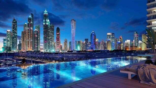 A nighttime cityscape with a reflective pool and modern buildings.
