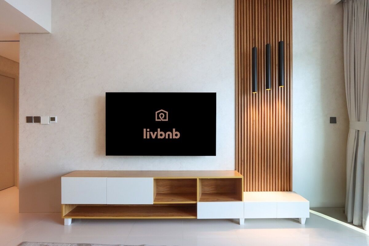 Una sala de estar moderna con un televisor de pantalla plana montado en la pared, una consola de madera minimalista y un panel de madera vertical.