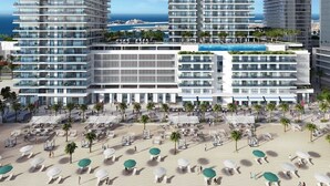 A modern hotel with multiple high-rise buildings, a central courtyard with palm trees, and a pool area.