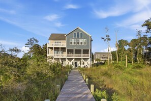 A two-story house with a wooden deck leading to the entrance.