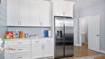 A kitchen with white cabinets, a stainless steel refrigerator, and a coffee maker.