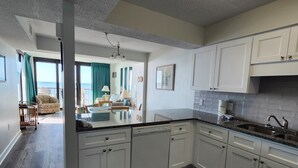 Eine moderne Küche mit weißen Schränken, einer Granit Arbeitsplatte und einem eingebauten Geschirrspüler.