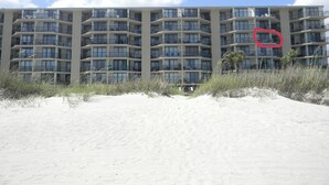 Ein mehrstöckiges Hotel mit Balkonen in der Nähe eines Sandstrandes.