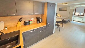 A modern kitchen with dark cabinets, a wooden countertop, and a coffee maker. - Lovely Old Town Studio (Hall in Tirol)