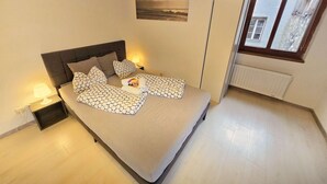 A bedroom with a bed, nightstands, a window, and a radiator. - Lovely Old Town Studio (Hall in Tirol)