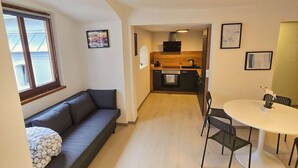 A modern apartment with a living area featuring a sofa and a dining table with chairs. - Lovely Old Town Studio (Hall in Tirol)