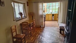 Una habitación acogedora con suelo de madera, una cama, una mesa de comedor con sillas, un sofá y un televisor.