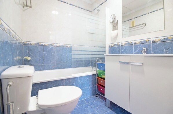 A bathroom with a toilet, bathtub, and a shower enclosure.