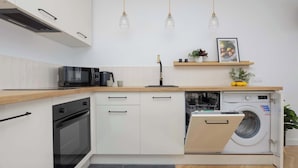Een compacte keuken met een magnetron, oven, vaatwasser en een ingebouwde wasmachine.