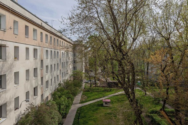 Un edificio de varios pisos con una hilera de ventanas y un pequeño jardín con árboles y un sendero.