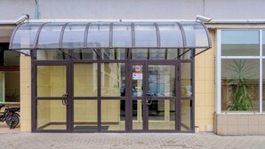 A building entrance with a glass door and a covered waiting area. - Comfortable Apartment in the Center | View of Skyscrapers, Air Conditioning (Warszawa)