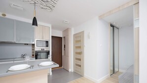 A modern kitchen with a central island, built-in microwave, and a dark pendant light. - Comfortable Apartment in the Center | View of Skyscrapers, Air Conditioning (Warszawa)