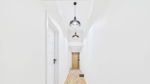Un pasillo con paredes blancas, piso de madera y felpudo negro en la entrada.