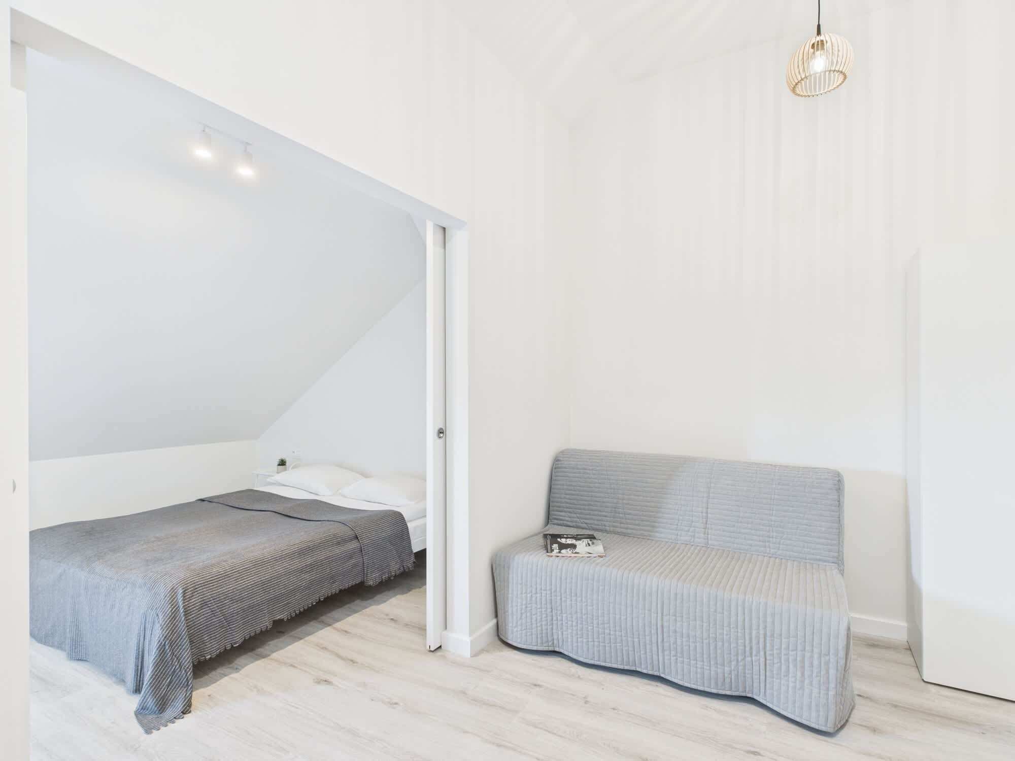 Un dormitorio pequeño y moderno con cama altillo, un banco e iluminación colgante.