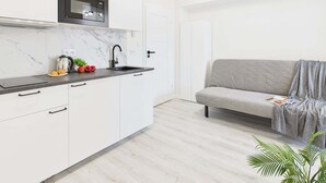 Eine moderne Küche mit weißen Schränken, einer schwarzen Arbeitsplatte und einer eingebauten Mikrowelle.