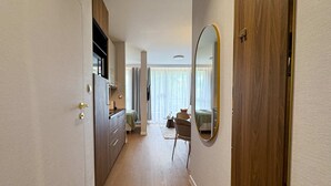 A hallway leading to a bedroom with a large mirror and a wooden wardrobe.