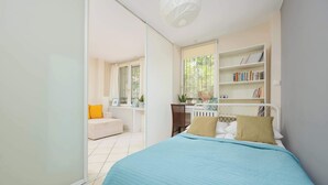 Un dormitorio con cama, escritorio, estantería y ventana.