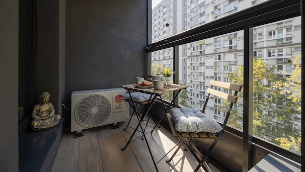 Un balcon avec une table, des chaises, une statue et un appareil de climatisation.