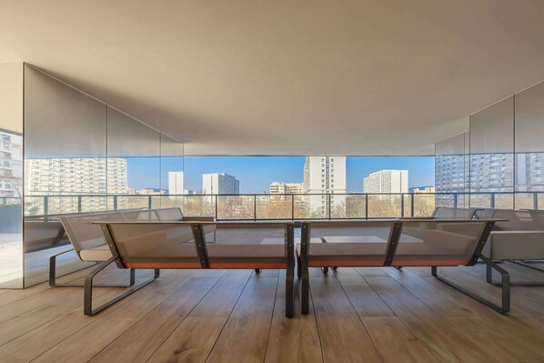 A modern dining area with a table and chairs, large windows offering a city view.