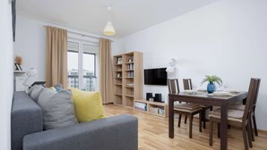 Una sala moderna con un sofá gris, una mesa de comedor de madera y una estantería.