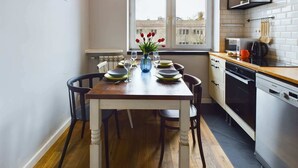 Una cucina compatta con un tavolo da pranzo per quattro persone, una finestra vista edifici ed elettrodomestici moderni.