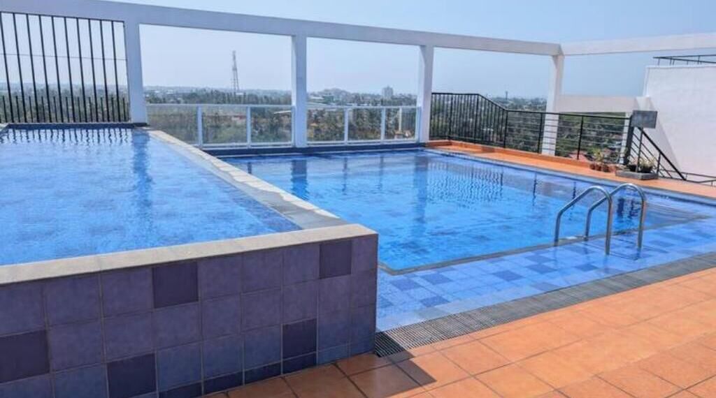 A rooftop swimming pool with a view of the city skyline.