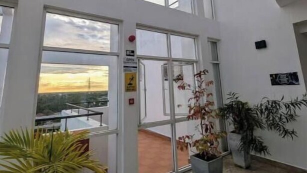 A spacious atrium with high ceilings and large windows, offering views of the sky and a sunset. - Urban 3BR Apt• Hi-Speed Wi-Fi• Roof Top Pool & Gym (Negombo)
