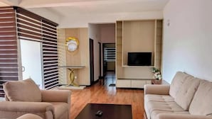 A modern living room with a sofa set, a coffee table, and a TV mounted on the wall. - Urban 3BR Apt• Hi-Speed Wi-Fi• Roof Top Pool & Gym (Negombo)
