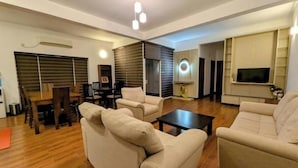 A modern living room with a sofa set, a coffee table, and a TV mounted on the wall. - Urban 3BR Apt• Hi-Speed Wi-Fi• Roof Top Pool & Gym (Negombo)